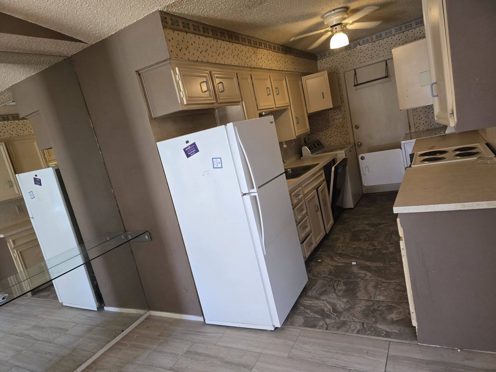 Kitchen after an 806 Cleanouts cleanout: empty counters, wood cabinets, a white refrigerator, and a cleared floor